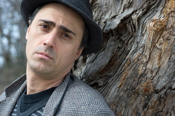 Portrait of Irakli Kakabadze wearing a hat, standing beside a tree